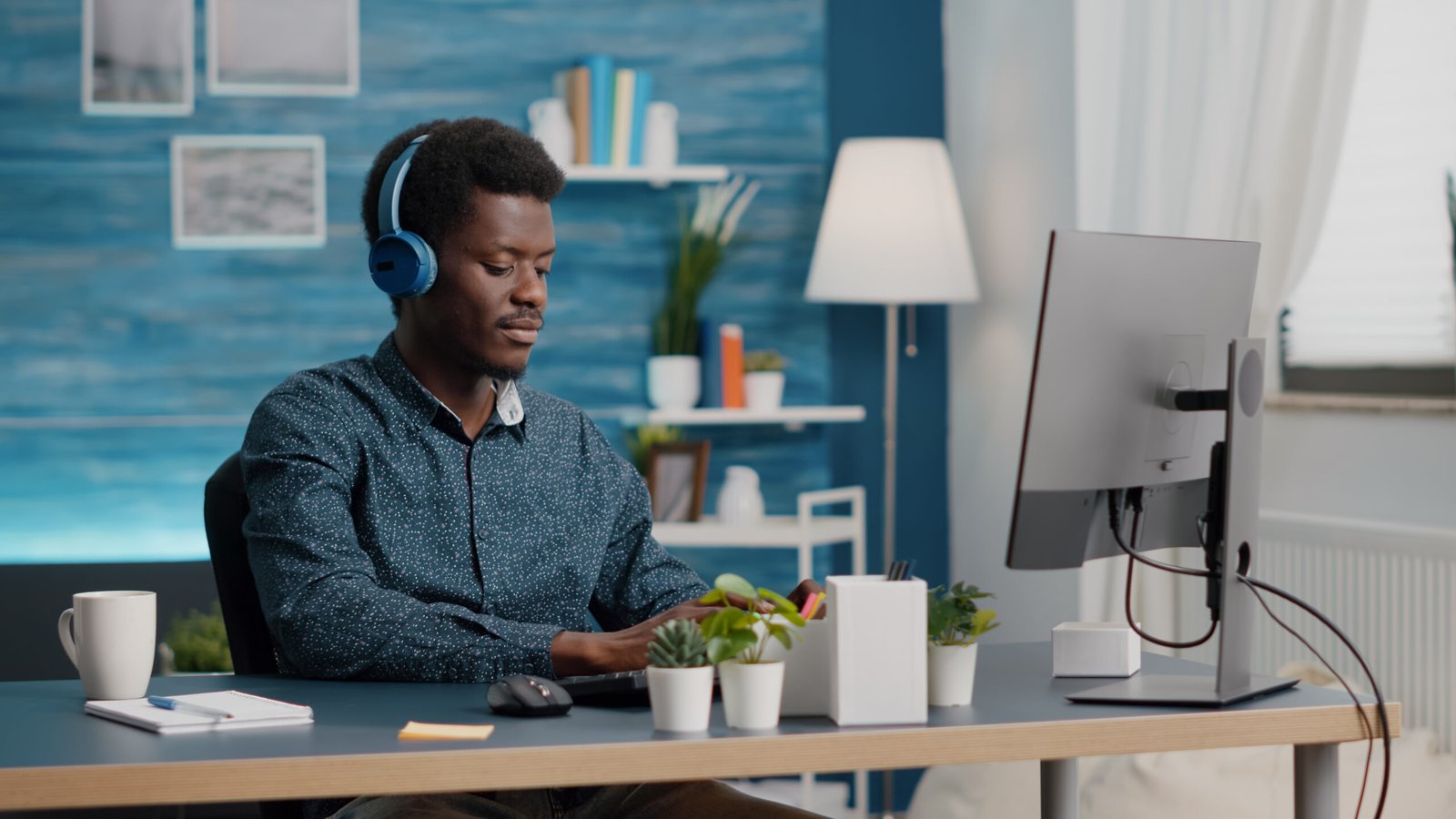 African american black manager using headphones to listen music while working from home office on computer PC